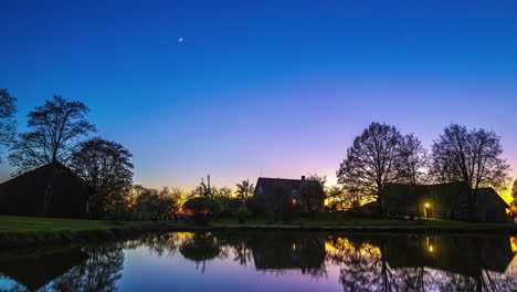 Timelapse-De-Día-A-Noche-Con-Puesta-De-Sol-Y-Puesta-De-Luna-Sobre-La-Cabaña-Cerca-Del-Estanque