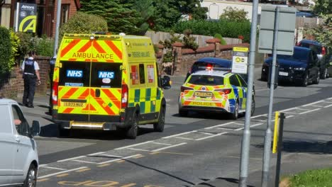 Coche-De-Policía-Y-Ambulancia-Paramédica-Que-Asisten-A-Un-Incidente-De-Tráfico-Peatonal-En-La-Calle-Británica