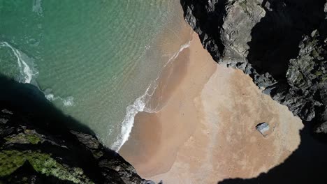 Cornwall-Cove-with-Beach-and-Rocky-Cliffs-from-an-Aerial-Top-Down-View-in-Slow-Motion,-UK