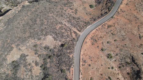 Panorámica-Aérea-De-Drones-Girando-Sobre-Una-Carretera-En-Un-Desierto-Con-Arena-Roja.