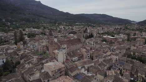 Aerial-forward-medieval-catholic-church-in-city-Soller,-Mallorca,-cloudy-day