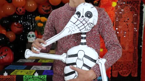 Holding-homemade-skeleton-figurine-for-Día-de-Muertos,-waving-its-hand