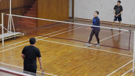 Gruppe-Von-Asiatischen-Männern-Training-Auf-Dem-Hallenplatz-Mit-Schlägern-Und-Federball