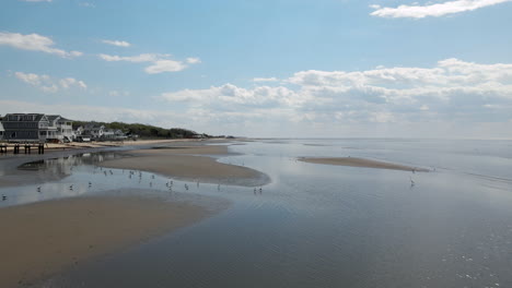 Aerial-Pass-Over-Crystal-Curves-of-Water-on-New-Jersey-Shore-with-Small-Birds-and-houses