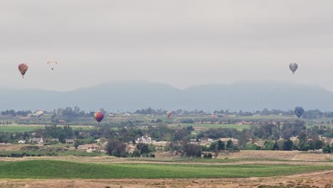 Festival-Del-Vino-Y-Globos-De-Temecula-Seis-Globos-Movimiento-De-Drones-De-Lado-A-La-Izquierda-El-Parapente-Entra-Desde-La-Izquierda