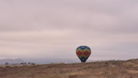 Globo-De-Temecula-Y-Festival-Del-Vino-Vista-Por-Drones-De-Un-Globo-Colorido-Llegando-Para-Aterrizar-Detrás-De-La-Colina