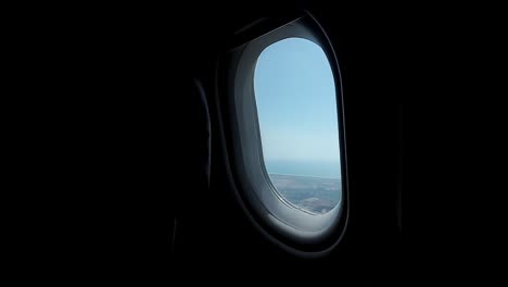 Dentro-De-La-Cabina-Del-Avión,-Nuestra-Mirada-Se-Encuentra-Con-La-Ventana,-Cuyo-Marco-Encierra-Un-Hermoso-Cielo-Azul.