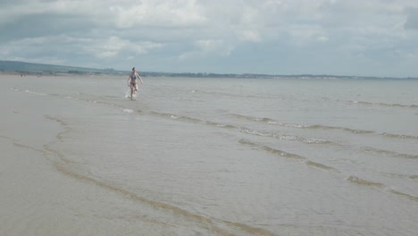 Along-secluded-shoreline-female-teenager-running-alone,-slow-motion
