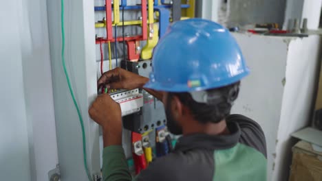 Ingeniero-Vestido-De-Azul-Con-Fuerza-Revisando-Los-Cables-En-La-Caja-De-Control-En-El-Almacén-De-La-Fábrica.