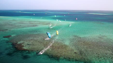 Múltiples-Kitesurfistas-Deslizándose-Sobre-Aguas-Cristalinas-De-Color-Turquesa-En-Los-Roques,-Cayo-Vapor,-Vista-Aérea