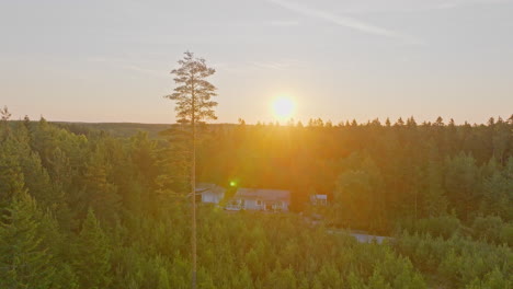 Luftaufnahme-Eines-Abgelegenen-Hauses-Mitten-Im-Wald,-Sonnenaufgang-Im-Hintergrund