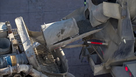 Close-up-of-a-concrete-mixer-truck-dumping-the-fresh-load-into-the-back-of-a-boom-pump-truck-in-slow-motion