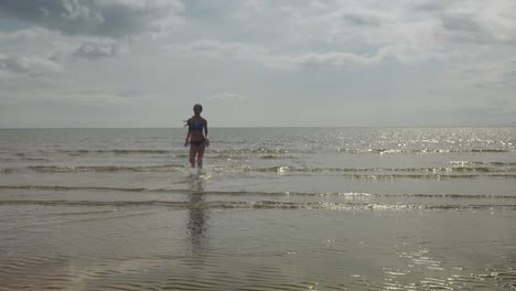 Young-girl-running,-ocean-water,-beach-location,-golden-sun,-slow-mo