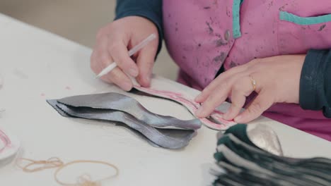 Worker-tracing-leather-pieces-using-a-cardboard-template-in-a-shoemaking-factory,-close-up