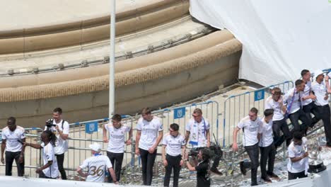 Real-Madrid-players,-Eduardo-Camavinga,-Aurelien-Tchouameni,-and-Jude-Bellingham,-use-a-microphone-to-talk-to-fans-during-the-36th-La-Liga-championship-celebration-at-Cibeles-Square