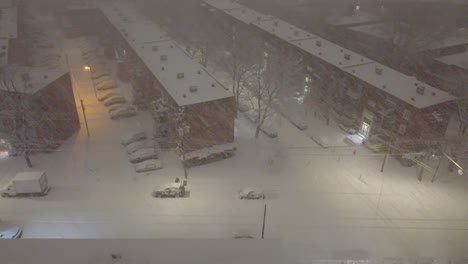 Winter-night-in-Montreal-with-snowfall-covering-streets-and-parked-cars,-cityscape