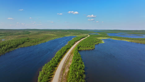 Drone-shot-of-a-road-in-middle-of-ponds-in-Kaldoaivi-wilderness,-summer-in-Lapland