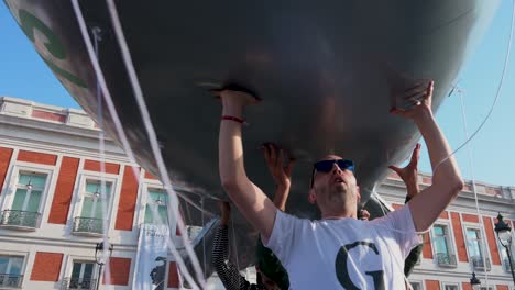 Protesters-at-Puerta-del-Sol-in-Madrid,-Spain,-demand-an-end-to-arms-sales-to-Israel,-with-some-holding-a-balloon-depicting-a-bomb-in-solidarity-with-Palestine