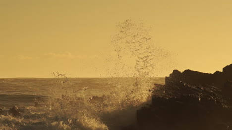 Olas-Del-Mar-Agitadas-Rompiendo-En-Las-Rocas-Creando-Un-Enorme-Rocío-Durante-La-Puesta-De-Sol-Dorada---Primer-Plano-Estático