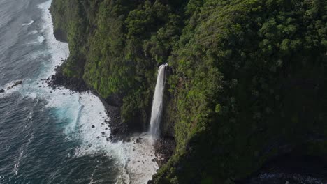 Waterfall-on-Maui-north-shore-plummets-down-cliff-onto-rocky-shore