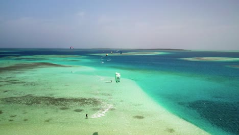 Kitesurfer-Auf-Dem-Lebhaften-Wasser-Von-Los-Roques,-Die-Den-Dynamischen-Kontrast-Des-Ozeans-Zur-Schau-Stellen,-Luftaufnahme