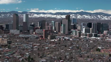 Downtown-Denver-Colorado-aerial-drone-neighborhood-streets-Spring-Mount-Blue-Sky-Evans-Front-Range-Rocky-Mountains-foothills-skyscrapers-daytime-sunny-clouds-backwards-slowly-motion