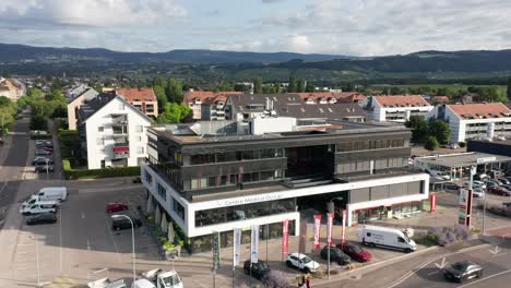 Drone-slowly-flies-away-from-Centre-Medical-du-Lac,-a-medical-office-building-in-Gland,-Switzerland