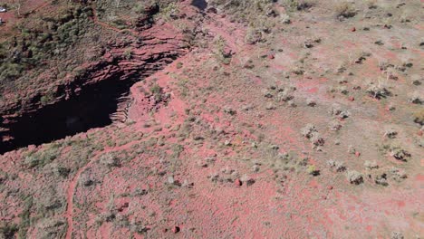 Drone-aerial-panning-down-over-Joffree-gorge-and-waterfall-in-Karijini-national-park-revealing-barren-land