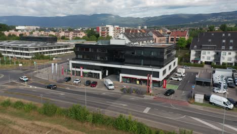 Antena-De-Un-Gran-Edificio-De-Oficinas-A-Lo-Largo-De-Una-Carretera-Tranquila-En-Gland,-Suiza