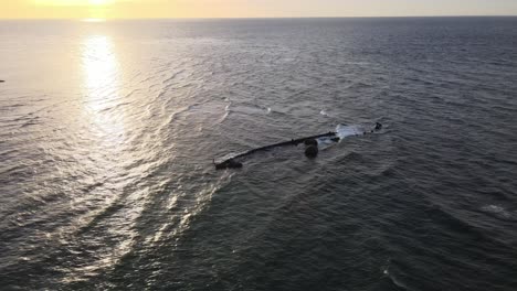 Drone-aerial-during-sunset-over-an-ocean-with-a-shipwreck