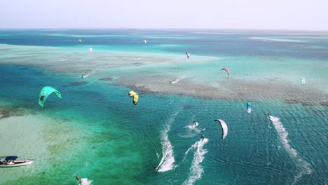 Coloridos-Kitesurfistas-Deslizándose-Sobre-Aguas-Cristalinas-En-Cayo-Vapor,-Vibrante-Escena-Oceánica,-Vista-Aérea