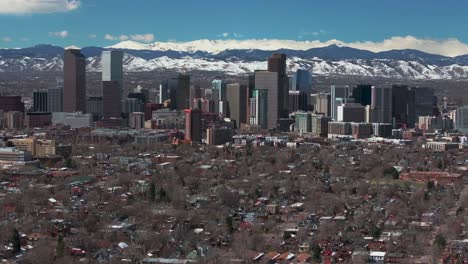 Downtown-Denver-Colorado-aerial-drone-neighborhood-streets-Spring-Mount-Blue-Sky-Evans-Front-Range-Rocky-Mountains-foothills-skyscrapers-daytime-sunny-clouds-forward-reveal-motion