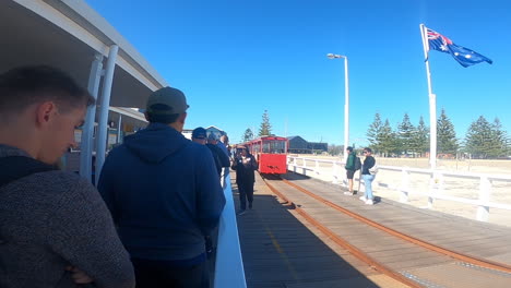 Los-Viajeros-Esperan-Pacientemente-En-Un-Muelle,-Listos-Para-Embarcarse-En-Un-Viaje-Panorámico-En-Tren-En-El-Embarcadero-De-Busselton-Bajo-El-Cielo-Azul-Claro.