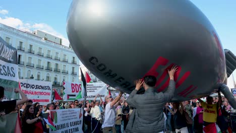 Auf-Der-Puerta-Del-Sol-In-Madrid-Demonstrieren-Demonstranten,-Die-Sich-Für-Palästina-Einsetzen,-Einige-Davon-Mit-Einem-Ballon,-Der-Eine-Bombe-Darstellt,-Für-Einen-Stopp-Der-Waffenverkäufe-An-Israel