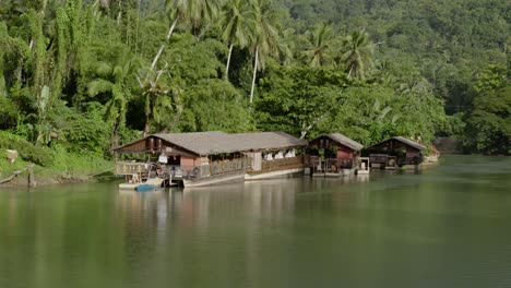 The-Loboc-River-in-the-Philippines-features-houses-built-on-its-surface,-nestled-amidst-lush-coastal-greenery