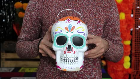 Holding-painted-skull-candy-bucket-for-mexican-Día-de-los-Muertos