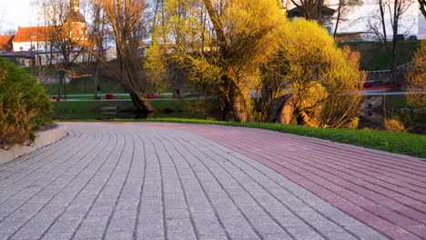 Pathway-in-Valmiera-park-during-golden-hour,-Latvia-in-low-angle-dolly-in-footage