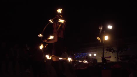 Female-acrobat-performs-with-rings-of-fire-in-front-of-an-audience-in-a-park