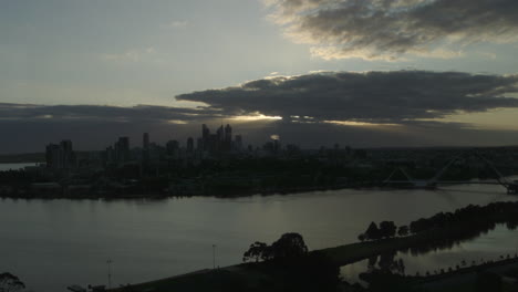 Horizonte-De-La-Ciudad-Al-Atardecer-Mientras-El-Sol-Brilla-A-Través-De-Las-Nubes-Y-Se-Refleja-En-El-Agua