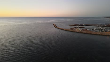 Drone-aerial-moving-slowly-over-the-ocean-during-sunset-over-Exmouth-harbour