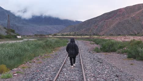 Hombre-Caminando-Solo-Por-Las-Vías-Del-Tren-En-Una-Zona-árida