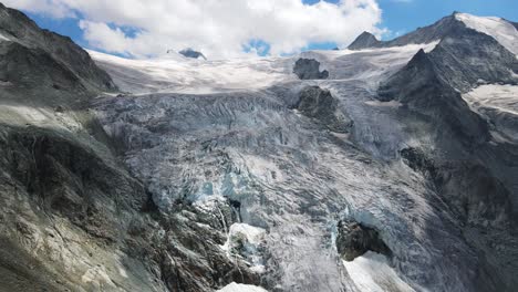 Majestuosa-Vista-Aérea-Del-Glaciar-Moiry-En-Suiza-Con-Impresionantes-Formaciones-De-Hielo-Y-Picos-Montañosos-Bajo-Un-Cielo-Azul