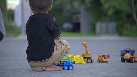 Unrecognizable-young-mexican-boy-barefoot-sitting-on-the-street-feeling-lonely-playing-with-his-car-toys-with-his-feet-dirty