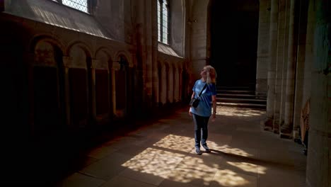 Sun-Light-shines-through-arched-church-window-to-female-cathedral-visitor