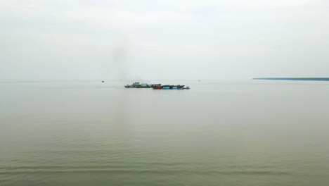 Distant-cargo-ship-dredging-sand-near-Kuakata,-Bangladesh,-with-visible-pollution,-overcast-skies