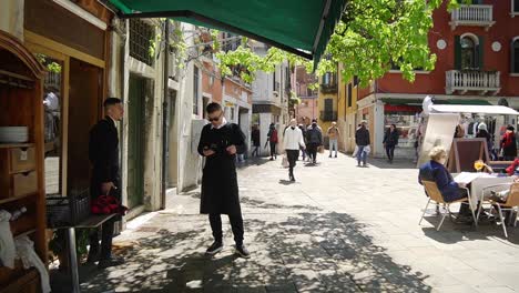 Waiters-outside-terrace-of-the-italian-restaurant-waiting-to-serve-tourist-customers-in-Venice