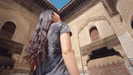 Asian-woman-impressed-by-the-architecture-of-Bou-Inania-Madrasa,-Fez