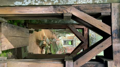 Vertical-view-walking-forward-POV-through-a-stone-gate-into-the-Prasat-Kraham-of-the-Koh-Ker-temple-ruins,-Cambodia