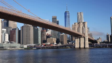 New-York-City-Brooklyn-Bridge-from-below-with-Lower-manhattan-and-Wall-Street-in-the-background-with-blue-sky-and-morning-sunrise