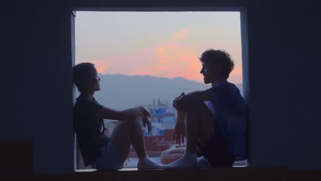 Pareja-Romántica-Mirándose-Sentados-En-La-Ventana-Al-Atardecer